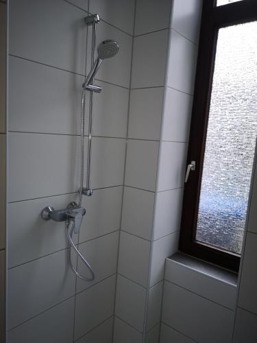 y baño de azulejos blancos con ducha y ventana. en Ferienwohnung im Erdgeschoss mit Terrasse, en Bremerhaven