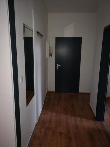 an empty room with a black door and wooden floors at Ferienwohnung im Erdgeschoss mit Terrasse in Bremerhaven