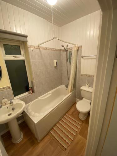 a bathroom with a sink and a tub and a toilet at Arman Lodge House in Peterborough