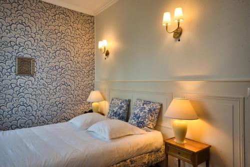 a bedroom with a bed with two lamps and a wall at Chateau de la Rozelle in Cellettes
