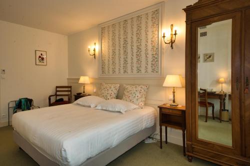 a bedroom with a bed and two lamps and a mirror at Chateau de la Rozelle in Cellettes