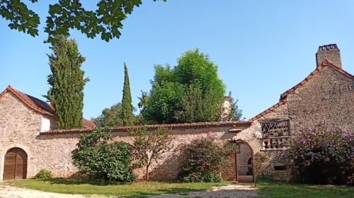 un antiguo edificio de piedra con árboles en el fondo en Les granges de l abbaye en Ginals