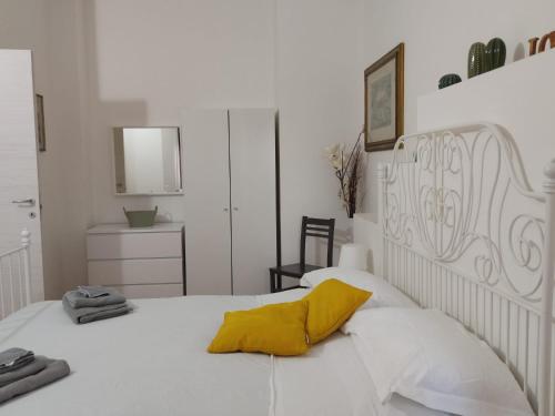 a bedroom with a white bed with a yellow pillow at Le casette di Frà al Bondì in Santa Severa