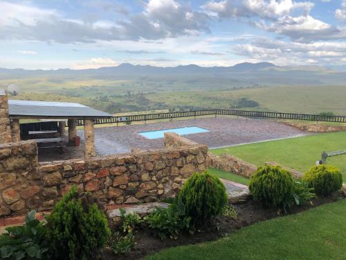 a stone building with a swimming pool and a stone wall at Uitzicht Private Nature Reserve and Lodge in Fouriesburg