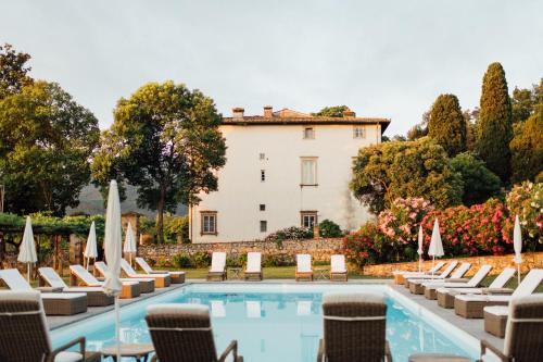 a villa with a pool and chairs and a building at Buonvisi B&B in Lucca
