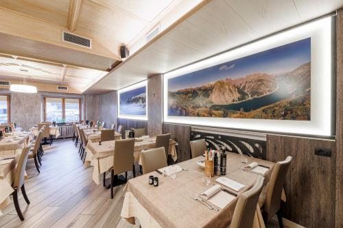 a restaurant with tables and chairs and a large painting on the wall at Hotel San Rocco in Livigno