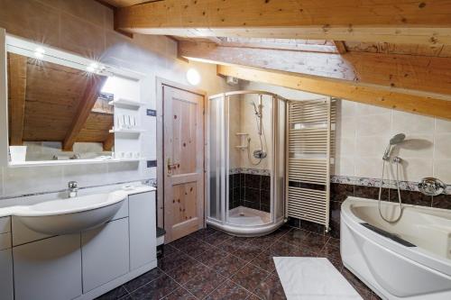 a bathroom with a shower and a sink and a tub at Hotel San Rocco in Livigno