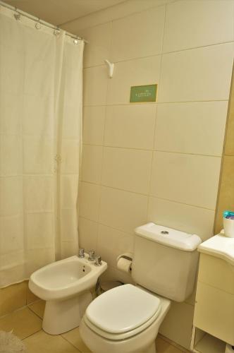 a white bathroom with a toilet and a sink at Uvas Apart Hotel in Mendoza