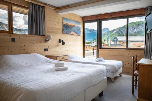 two beds in a room with mountains in the background at Hôtel Restaurant Saint Roch in Puy-Saint-Vincent