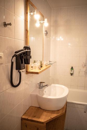 La salle de bains est pourvue d'un lavabo et d'un téléphone mural. dans l'établissement Hôtel Restaurant Saint Roch, à Puy-Saint-Vincent