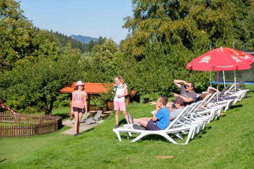 a group of people sitting on lawn chairs under an umbrella at Gästehaus Schlegel in Gunzesried