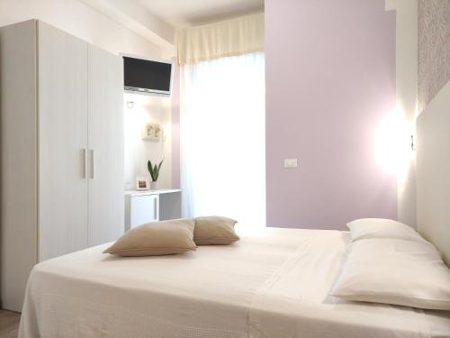 een slaapkamer met een bed met witte lakens en een raam bij Hotel Galassia in Rimini