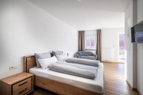 a bedroom with a bed and a chair at Kaneder Hof - Self Check-in in Inchenhofen