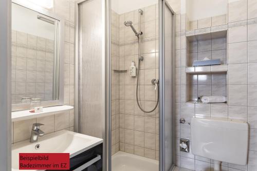 a bathroom with a shower and a toilet and a sink at Hotel & Restaurant Villa Ulmenhof in Bredstedt