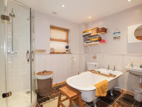 a bathroom with a tub and a shower and a sink at Bogindour Cottage in Muir of Ord