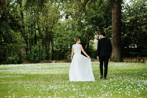 a bride and groom walking through a field of flowers at Villa Il Padule in Bagno a Ripoli