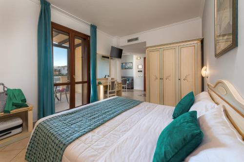 a bedroom with a large bed with green pillows at Helios Hotel in San Vito lo Capo
