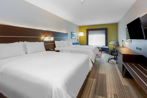 a hotel room with two beds and a flat screen tv at Holiday Inn Express Hotel & Suites Woodhaven by IHG in Woodhaven
