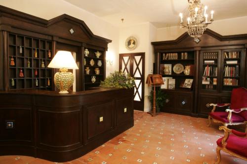 Habitación con biblioteca, armarios de madera y lámpara. en Hotel Villa Dorata, en Nicolosi