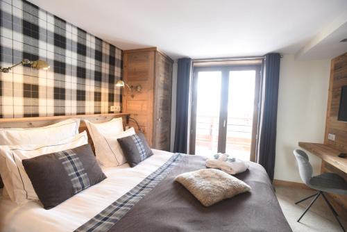 a bedroom with a bed with pillows and a window at Hotel La Toviere in Val dʼIsère