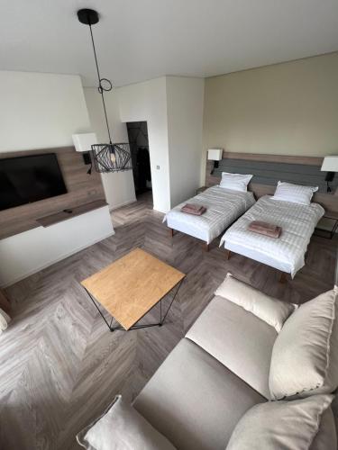 uma sala de estar com três camas e um sofá em MOYA Apartmentai em Naujoji Akmenė