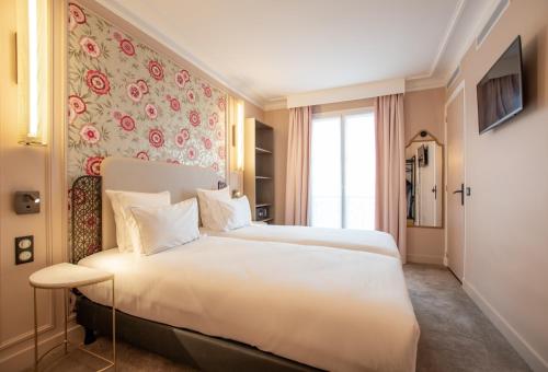 a bedroom with a large white bed and a floral wall at ELSA, Hôtel Paris in Paris