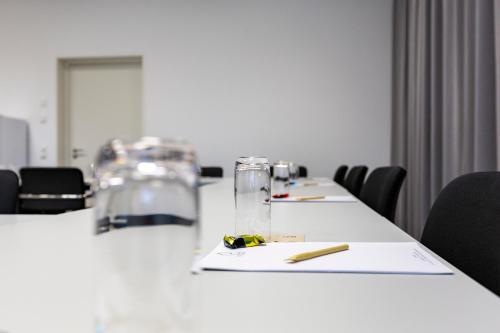 a meeting room with two tables with glasses and a pencil at Hotel MODI in Dachau