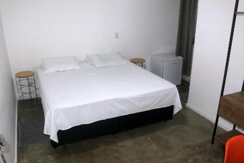 a bedroom with a bed with white sheets and two chairs at Hotel Laundos in Sao Paulo