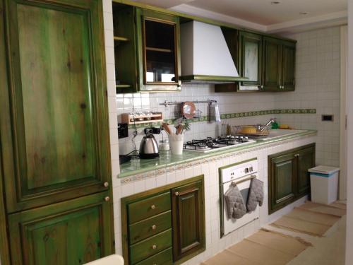 cocina con armarios verdes y fogones en Casa Luthi, en Siracusa