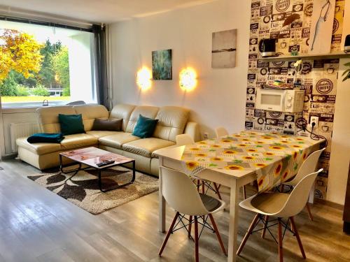 uma sala de estar com uma mesa e um sofá em Moderne und komfortable Appartements im Ferienpark Hahnenklee em Hahnenklee-Bockswiese