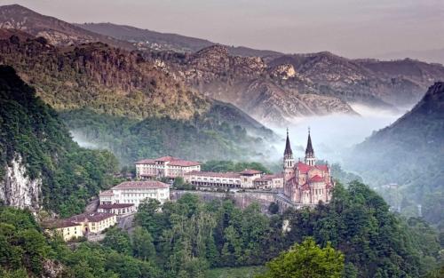 ein Schloss auf einem Hügel mit Bergen im Hintergrund in der Unterkunft Apartamento Rural Lago Enol in Cangas de Onís