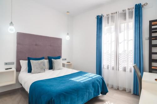 1 dormitorio con 1 cama grande y cortinas azules en Amphora Alojamiento Ecija, en Écija