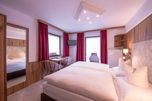 a bedroom with a large white bed and red curtains at Das Elisabeth in Sankt Anton am Arlberg