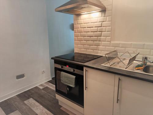 a kitchen with a stove top oven next to a sink at Location G&W, très proche sanctuaires in Lourdes