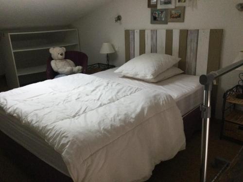 un lit avec un ours en peluche assis dans une chaise dans l'établissement Studio en Provence avec piscine, à Graveson