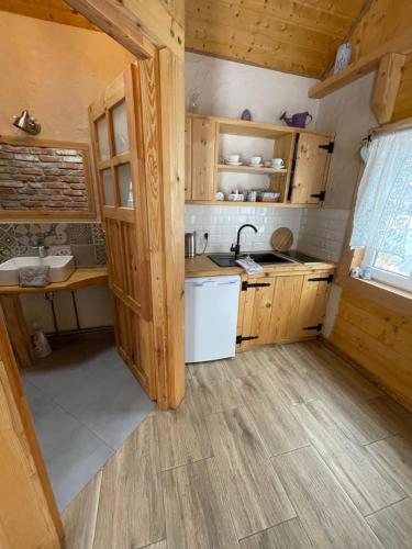 una pequeña cocina con armarios de madera y fregadero en Myczkowianka Sadyba, en Uherce Mineralne