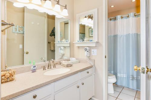 een badkamer met een wastafel, een toilet en een spiegel bij E201 - Tropical Shores in Oceanside