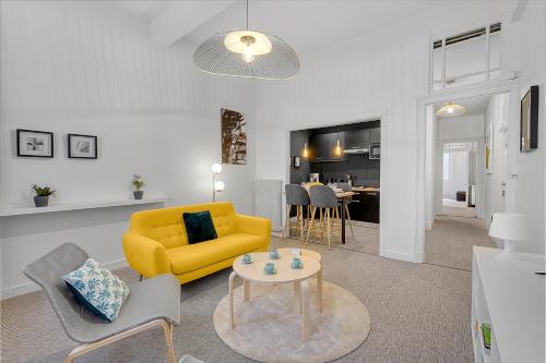 un salon avec un canapé jaune et une table dans l'établissement LE PLAISANCIER - T3 entièrement rénové de 60m3, à Toulouse