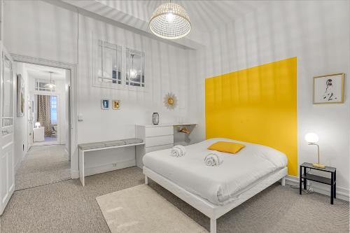une chambre avec un lit blanc et un mur jaune dans l'établissement LE PLAISANCIER - T3 entièrement rénové de 60m3, à Toulouse