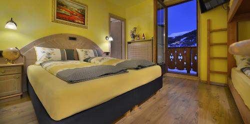 a bedroom with a large bed and a large window at Hotel Piccolo Mondo in Livigno