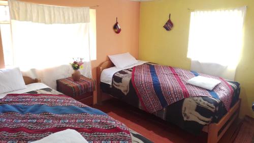 1 dormitorio con 2 camas y 2 ventanas en Ñustas de Piuray, en Urubamba