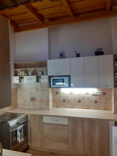 a kitchen with white cabinets and a microwave at Adél Apartman in Kaposvár