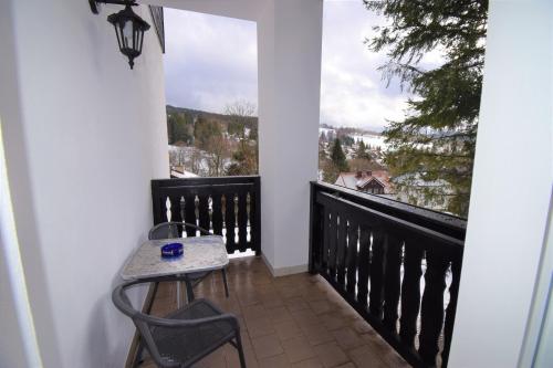 a balcony with a table and chairs and a large window at Pension St. Moritz in Železná Ruda