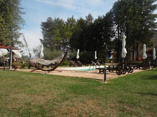 a park with a hammock and a swimming pool at Podere Caldaruccio La Pineta in Bosco