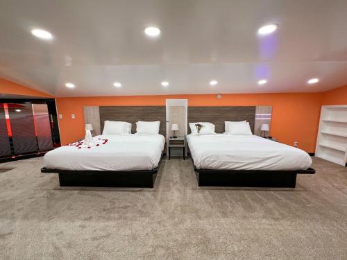 two beds in a room with orange walls at Hollywood Motel in Farmingdale