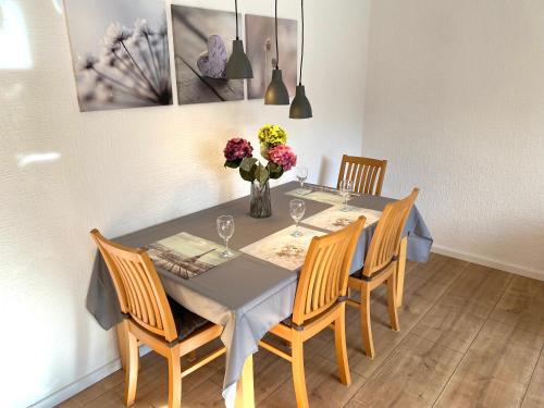 una mesa de comedor con sillas y un jarrón de flores en Stylisches Apartment ✰ SKYWALK ✰ mit Parkplatz en Willingen