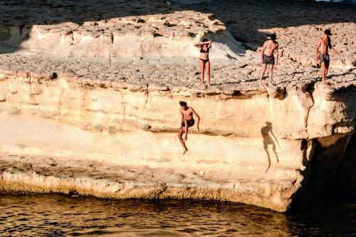 a group of men jumping off a cliff into the water at The Diplomat Hotel in Sliema