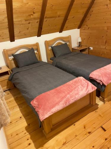 two beds in a room with wooden floors at Planinska kuca Popovic 3 in Ljuboš
