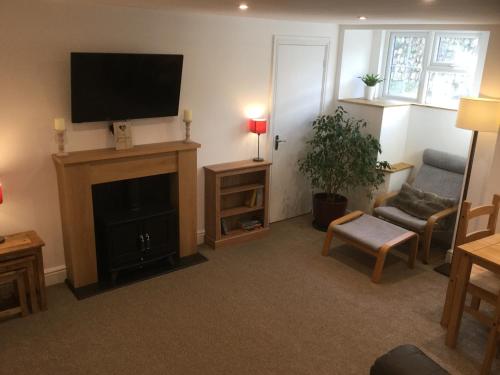 a living room with a fireplace and a flat screen tv at Crossways Corner Cottage in Gunnislake