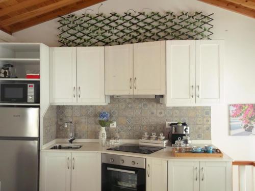 a kitchen with white cabinets and a stove top oven at Alo Baía São Lourenço in Santa Bárbara